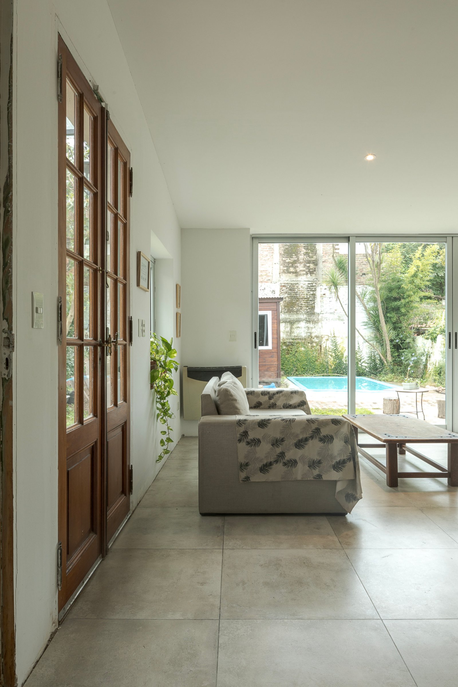 Sala de estar moderna com portas de correr e jardim com piscina — projeto Reforma Navarro, por Estudio YME, em B1648 Tigre